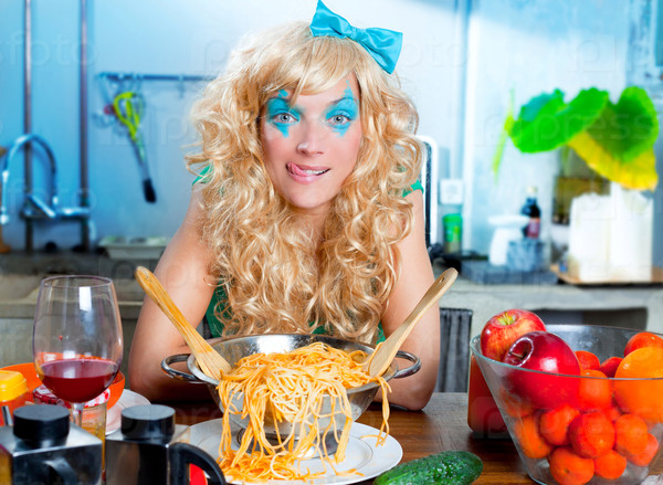 Blonde hungry girl funny on kitchen with pasta and fashion blue makeup