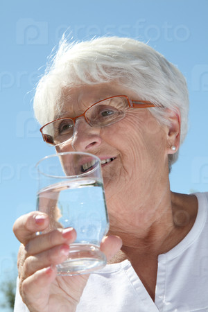 Closeup of elderly woman drinking water from a glass