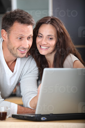 Couple at home connected on internet with laptop computer
