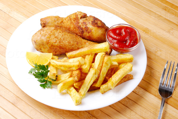 Fried chicken drumsticks and french fries with ketchup