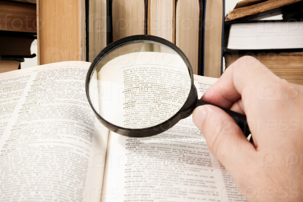 Educational concept (selective focus on some words of dictionary (center of magnifying glass)), stock photo