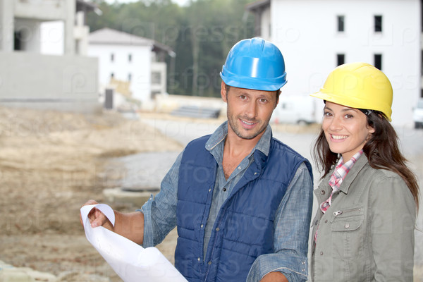 Team of architects checking plans on site, stock photo