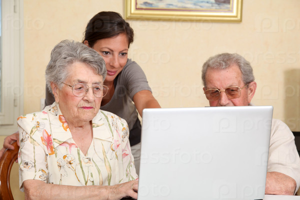 Couple of elderly persons with young woman using internet