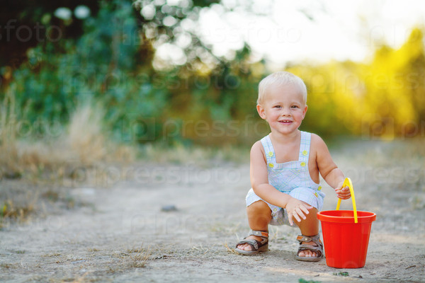 Little smiling boy with toy bucket outdoors