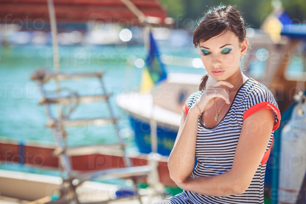 Beautiful sexy woman wearing sailor striped dress posing at the sea