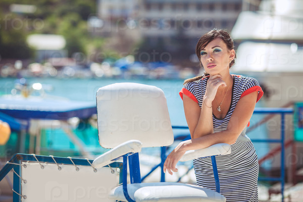 Beautiful sexy woman wearing sailor striped dress posing at the sea