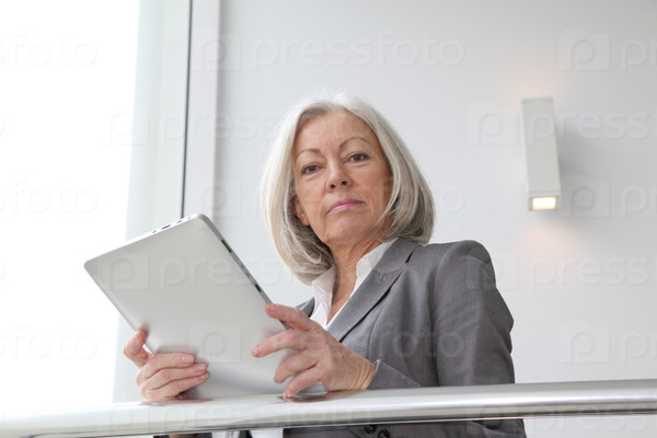 Senior businesswoman using electronic tablet in hall