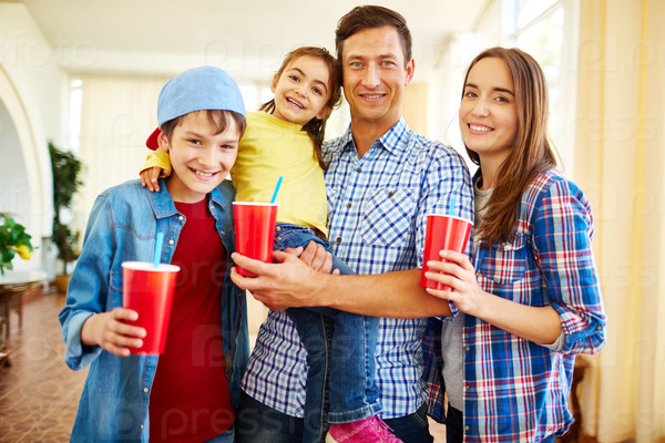 Modern family of four holding red glasses with drinks