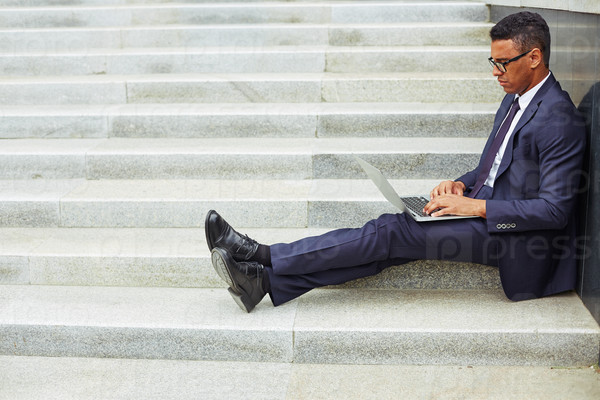 Young businessman using laptop while sitting on stairs