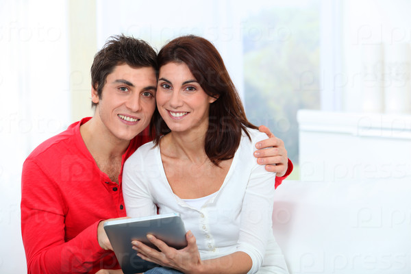 Young couple using electronic tab on sofa