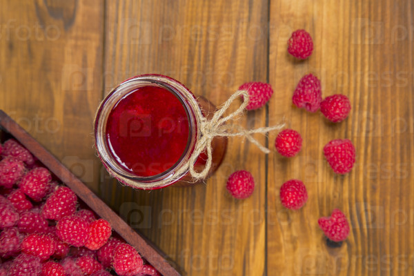 raspberries and raspberry jam on a wooden table