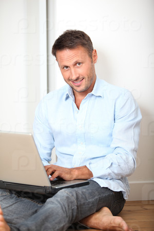 Man sitting on the floor at home with laptop computer