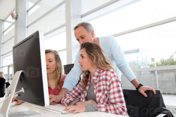 Students and teacher in in front of computer at school