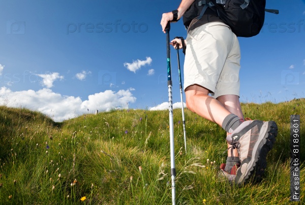 Male hiker walking along a mountain path. Horizontal orientation. Low angle view