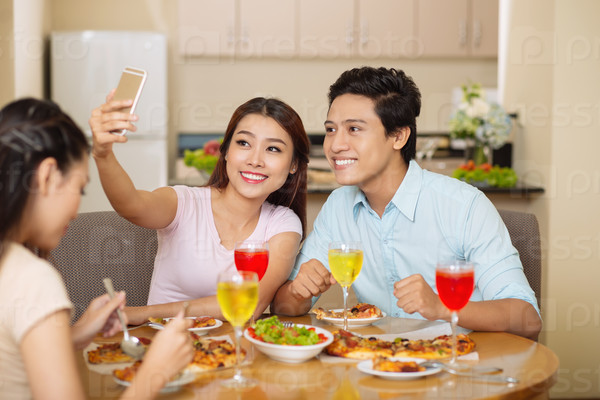 Young people taking selfie at the dinner with friends