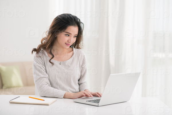 Young Vietnamese girl working on laptop at home