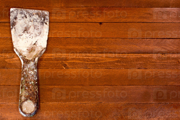 Rusty dirty spatula scraper toolon a brown wooden background. Copy space to right.