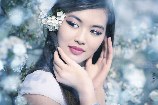 Young woman with cherry flowers. Soft blue tint.