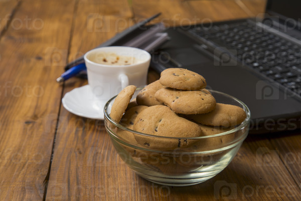 computer a cup of coffee and cookies on wooden table