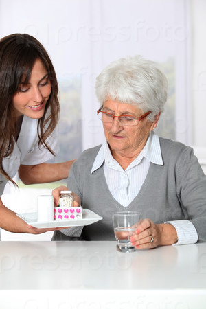 Nurse bringing medicine to elderly woman