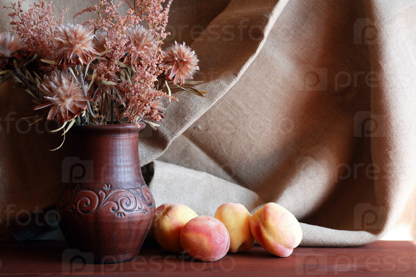 Nice bouquet of dry flowers in ceramic vase and freshness peach fruits