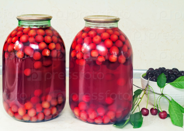 Home canning: large glass cylinders with cherry compote.