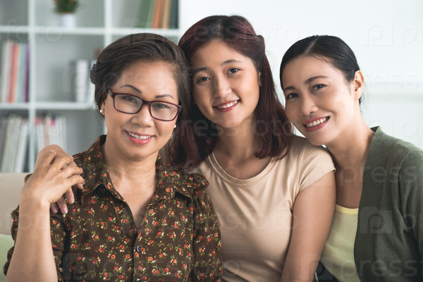 Close-up portrait of three women generations smiling and looking at the camera