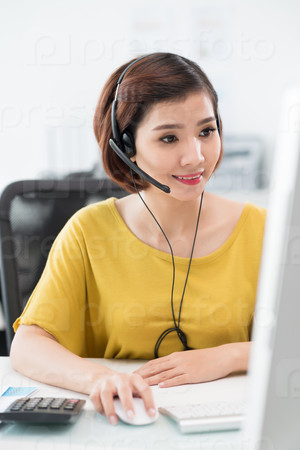 Portrait of Vietnamese business lady in headset working on computer