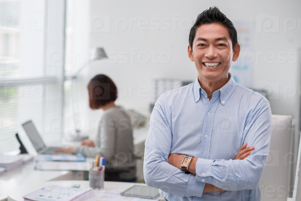 Portrait of cheerful middle-aged businessman standing in the office