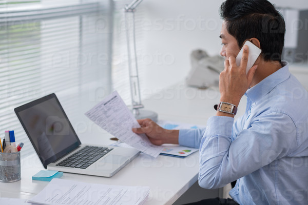 Office worker calling on the phone and reading business document