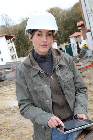 Woman engineer with white security helmet standing on construction site