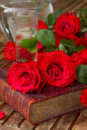 vintage old book  on table with red roses and long drink