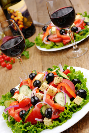 Greek salad and glass of red wine on the kitchen table