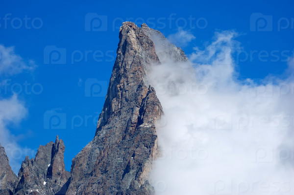 Aiguille Noire (Mont Blanc, Italy) rocky peak, while a growing cloud try to climb it.