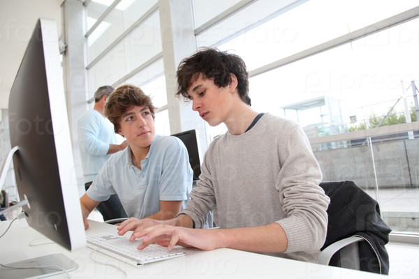 Teenagers in classroom working on desktop computer