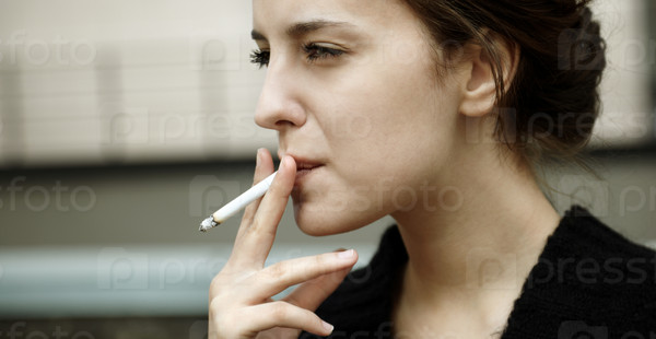 real young woman smokes on the street, selective focus