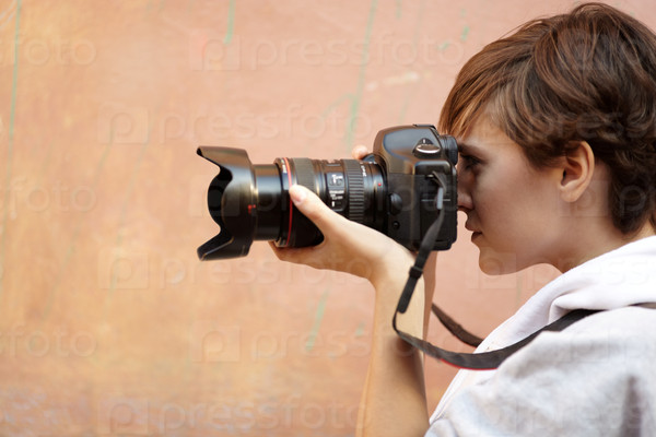 Female photographer with professional SLR camera, natural light, selective focus on eye, stock photo