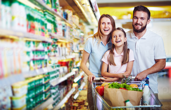 Ecstatic family with shopping cart with food visiting supermarket