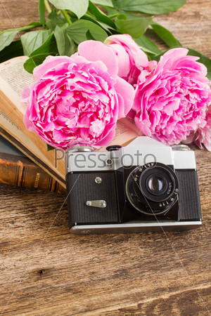 old  photo camera with books and fresh peony flowers