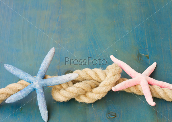 marine rope with blue and pink starfish on wooden background with copys space