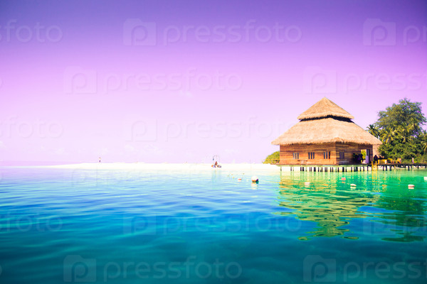 Overwater bungalows on the tropical island resort of Maldives at night.  Scenic sunset over the Ocean.