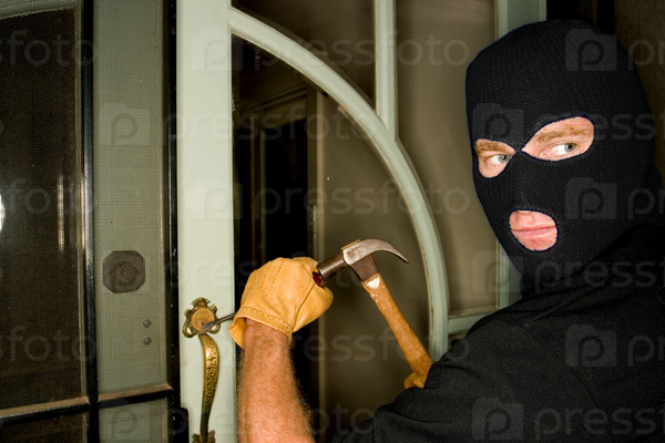 A burglar robbing a house wearing a balaclava.