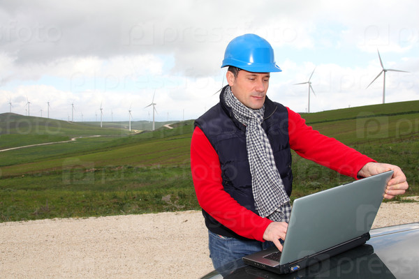 Engineer working on laptop computer in wind turbines field
