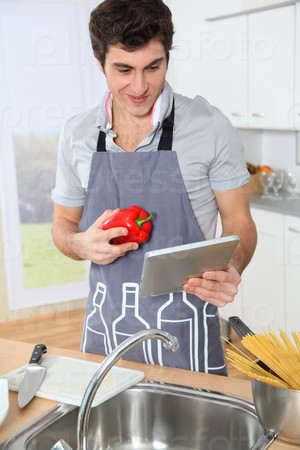 Man in kitchen looking at recipe on electronic tab