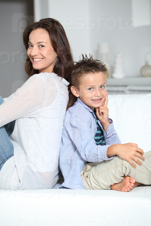 Little blond boy sitting on sofa with mom