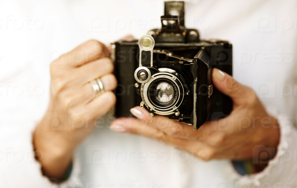 Woman hands with old film camera ,selective focus point on lens ,natural light, stock photo