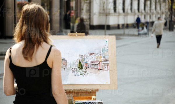 Young woman painting outside, focus point on image, stock photo