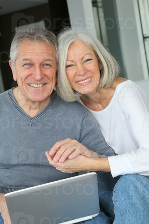 Senior couple sitting in sofa with laptop computer