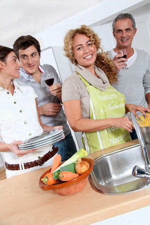 Group of friends preparing dinner in home kitchen