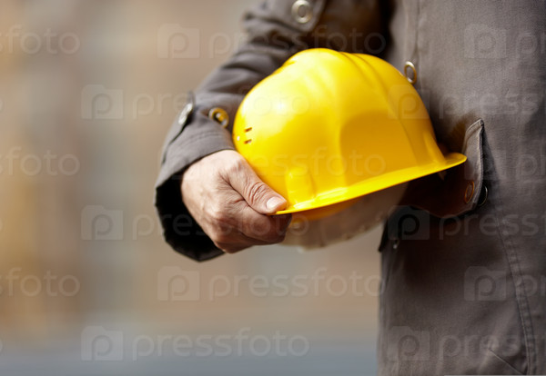 Hand of builder with yellow hardhat, natural light,selective focus, stock photo